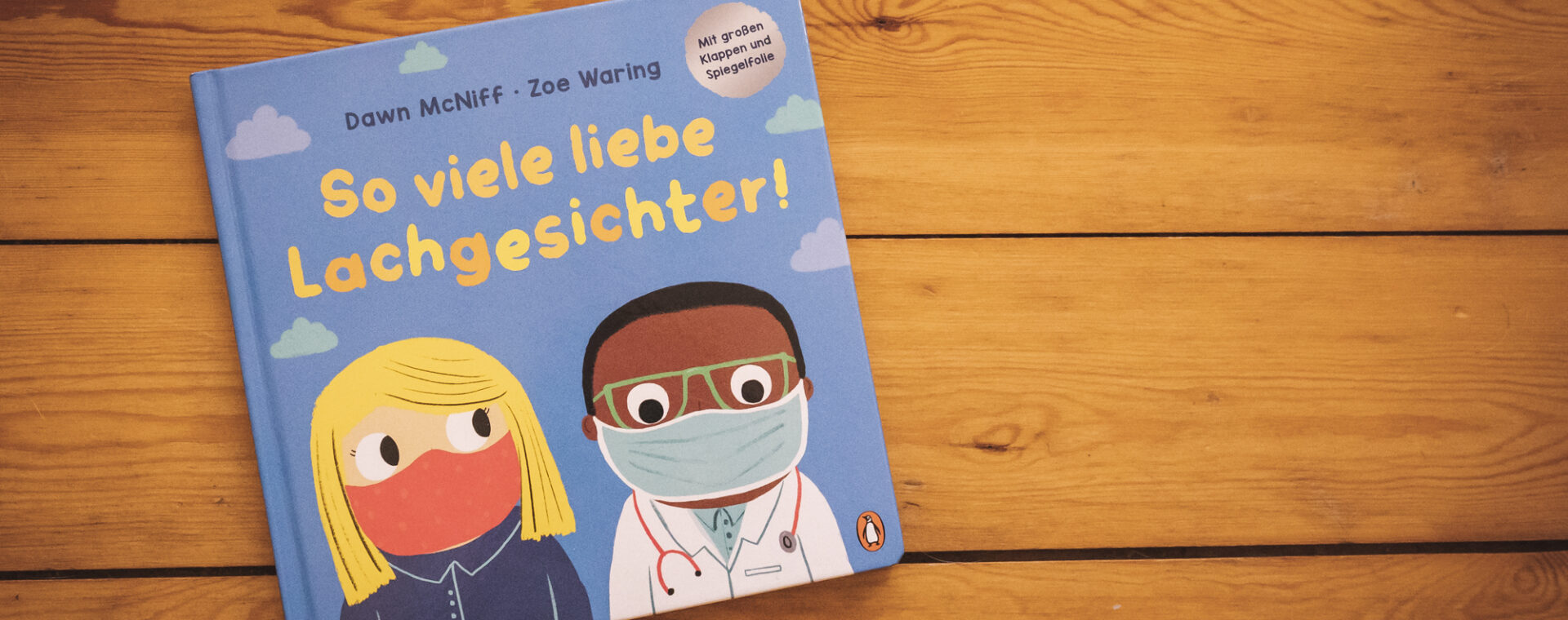 Das Buch-Cover von "So viele lieb Lachgesichter" zeigt zwei gezichente Menschen mit Maske, eine weiße Frau und einen Schwarzen Mann